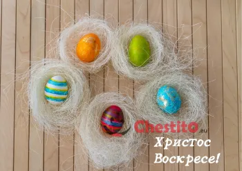 Картичка за Великден  цветни яйца в бели гнезда на дървен фон 